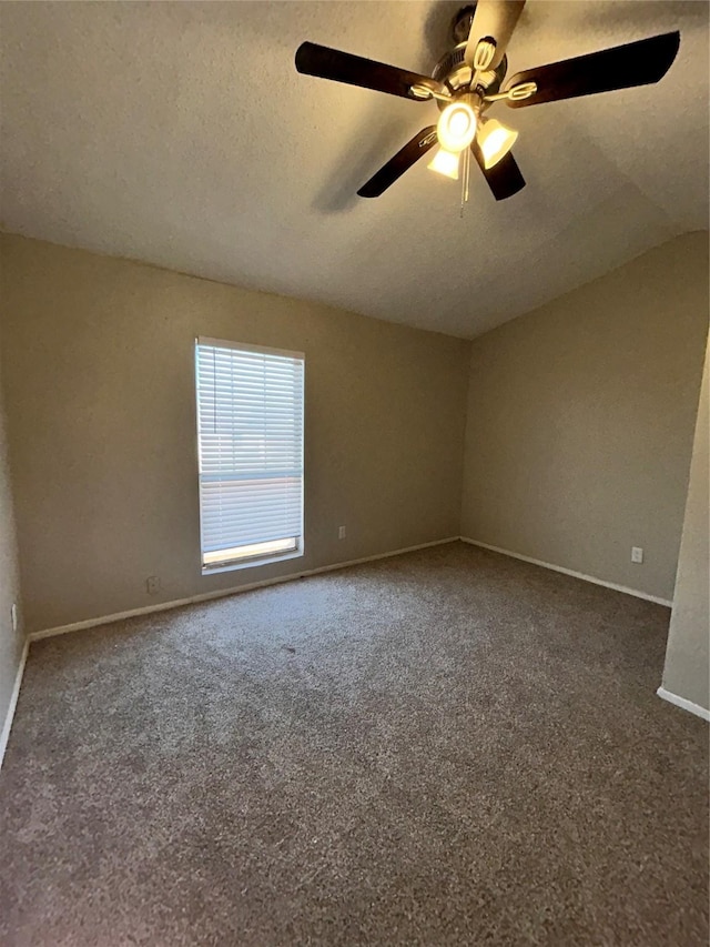 spare room with ceiling fan, dark carpet, lofted ceiling, and a textured ceiling