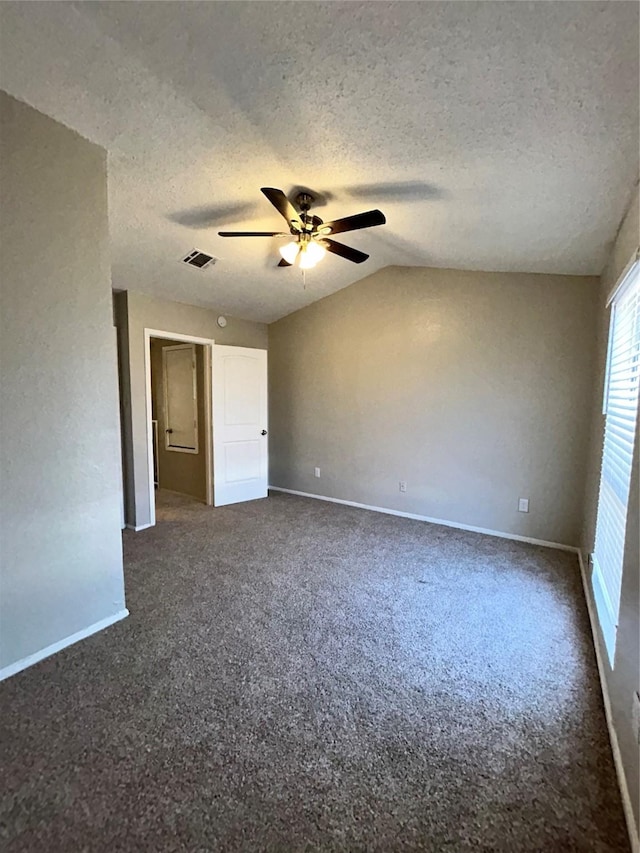 spare room featuring ceiling fan, dark carpet, a textured ceiling, and lofted ceiling