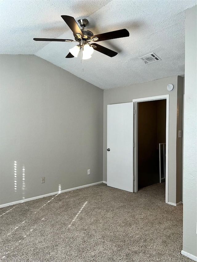 carpeted spare room with a textured ceiling, vaulted ceiling, and ceiling fan