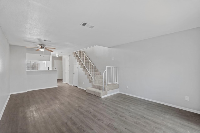 unfurnished living room featuring ceiling fan, dark hardwood / wood-style floors, and a textured ceiling