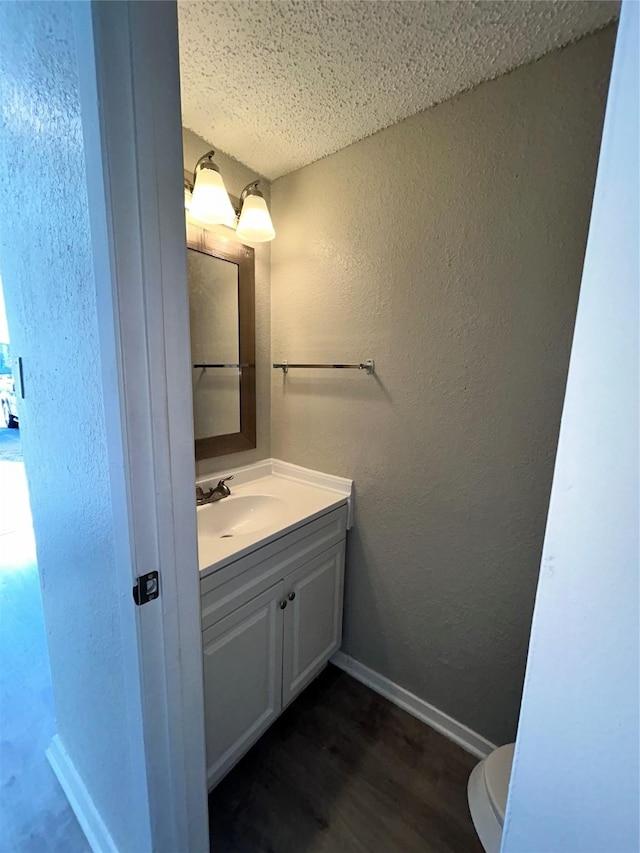 bathroom with hardwood / wood-style flooring, a textured ceiling, toilet, and vanity