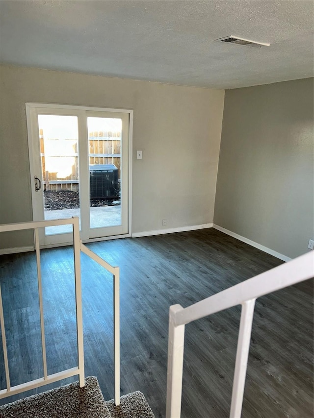 unfurnished room featuring a textured ceiling and dark hardwood / wood-style floors