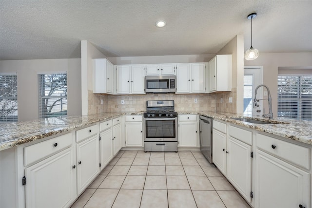 kitchen featuring kitchen peninsula, sink, decorative light fixtures, white cabinetry, and stainless steel appliances