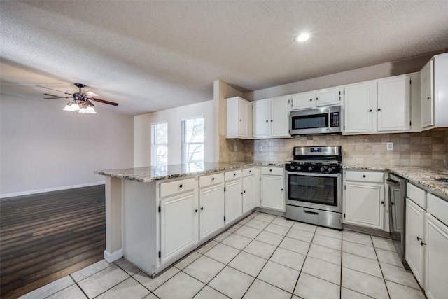 kitchen featuring kitchen peninsula, white cabinets, and appliances with stainless steel finishes