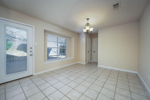 unfurnished dining area with a wealth of natural light, a textured ceiling, a chandelier, and light tile patterned flooring