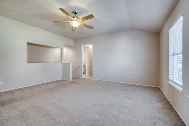 carpeted empty room with a textured ceiling, vaulted ceiling, and ceiling fan