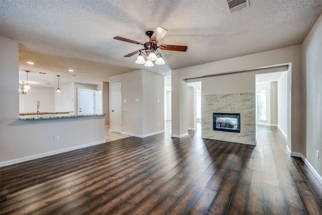 unfurnished living room with ceiling fan, a textured ceiling, dark hardwood / wood-style flooring, and a premium fireplace