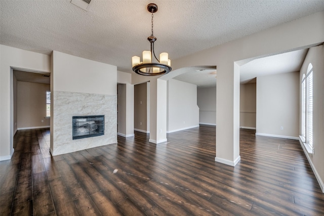 unfurnished living room featuring a premium fireplace, a wealth of natural light, a notable chandelier, and a textured ceiling