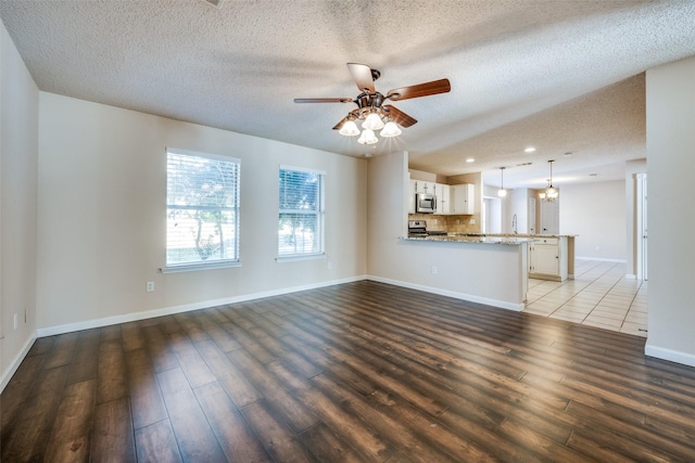 unfurnished living room featuring sink, ceiling fan, dark wood-type flooring, and a textured ceiling