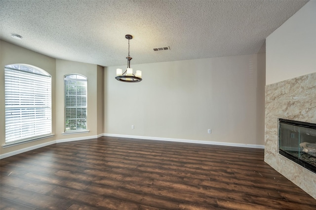 unfurnished dining area featuring a textured ceiling, dark hardwood / wood-style floors, a wealth of natural light, and a premium fireplace