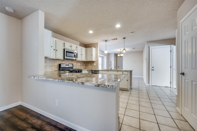 kitchen with decorative light fixtures, white cabinets, kitchen peninsula, and stainless steel appliances