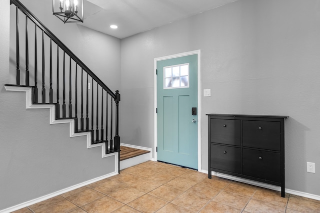 foyer entrance with light tile patterned floors and an inviting chandelier