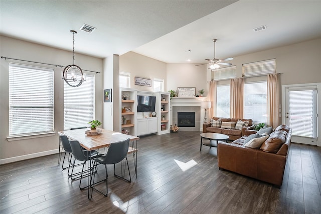 dining area featuring plenty of natural light, ceiling fan with notable chandelier, and dark wood-type flooring