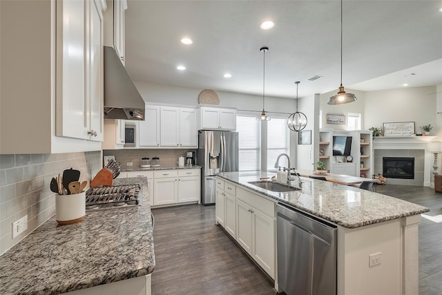 kitchen featuring hanging light fixtures, appliances with stainless steel finishes, sink, white cabinetry, and an island with sink