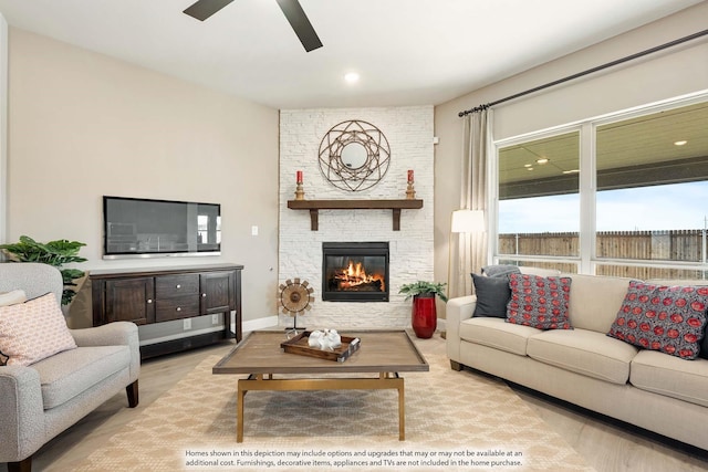 living room with a fireplace, light hardwood / wood-style floors, and ceiling fan