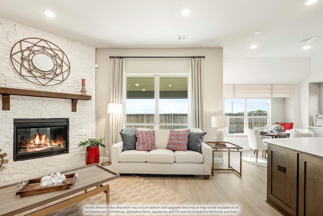 living room with a stone fireplace and light hardwood / wood-style floors