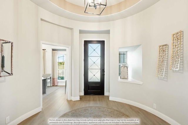 foyer entrance with an inviting chandelier, light hardwood / wood-style floors, and a tray ceiling