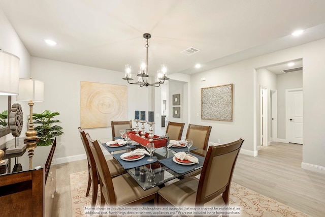 dining room with light hardwood / wood-style flooring and an inviting chandelier