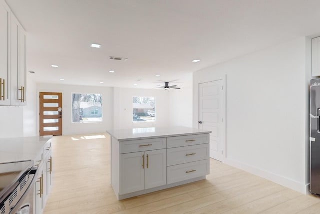 kitchen with white cabinets, light wood-type flooring, ceiling fan, and appliances with stainless steel finishes