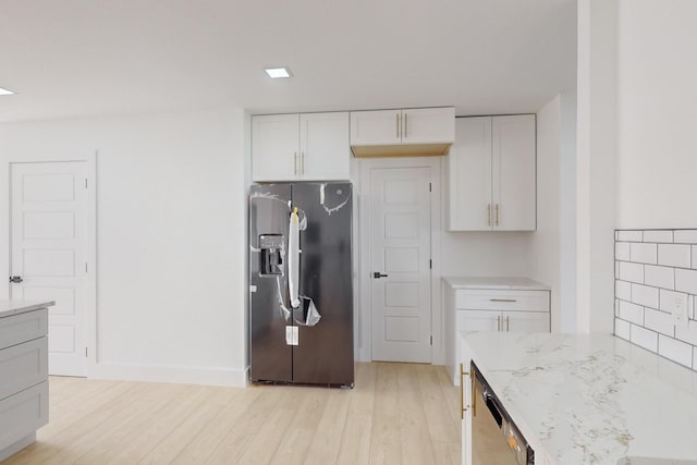 kitchen featuring black refrigerator with ice dispenser, light hardwood / wood-style floors, light stone countertops, dishwasher, and white cabinetry