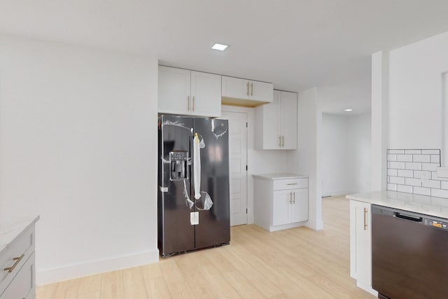 kitchen with black appliances, white cabinetry, decorative backsplash, light stone counters, and light hardwood / wood-style flooring