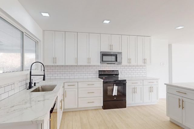 kitchen with light stone countertops, sink, white cabinets, backsplash, and stainless steel appliances