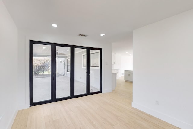 empty room featuring light hardwood / wood-style flooring, a wall of windows, and french doors