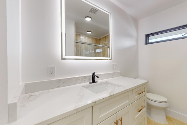 bathroom with hardwood / wood-style flooring, toilet, walk in shower, and vanity