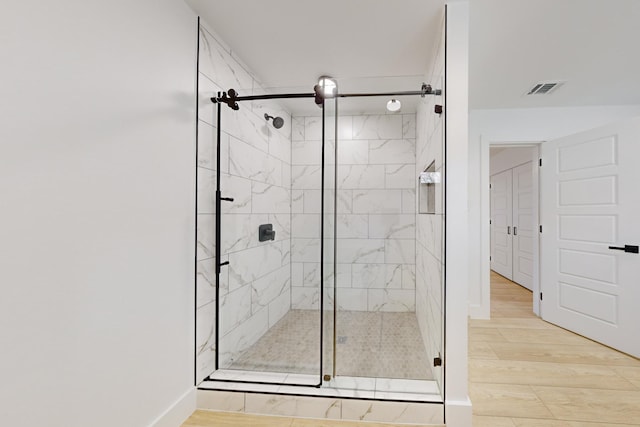 bathroom with hardwood / wood-style flooring and a shower with door