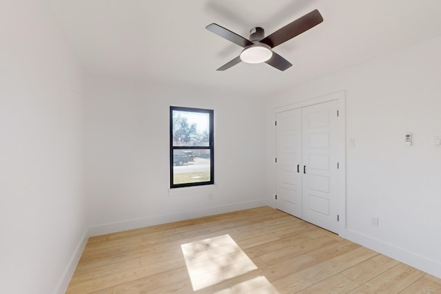 unfurnished bedroom featuring ceiling fan, light hardwood / wood-style floors, and a closet