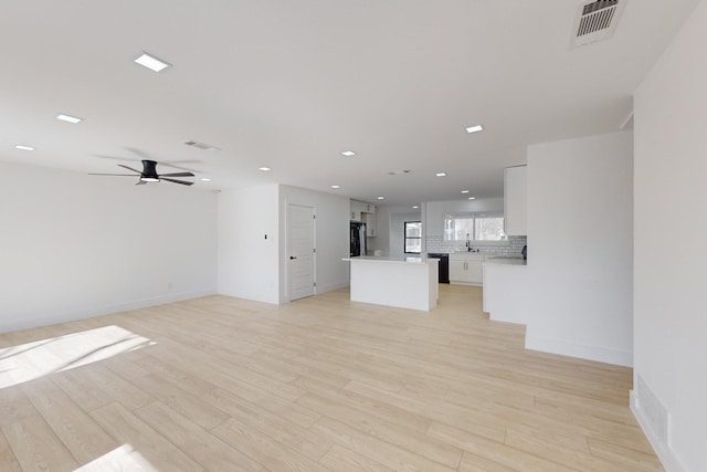 unfurnished living room featuring sink, light wood-type flooring, and ceiling fan