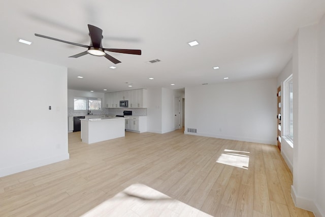 unfurnished living room with sink, ceiling fan, and light hardwood / wood-style flooring