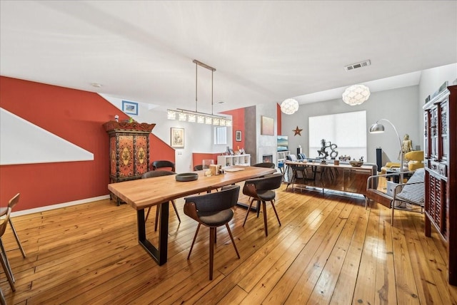 dining space with a tiled fireplace, light hardwood / wood-style flooring, and a wealth of natural light