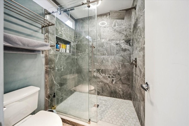 bathroom featuring a shower with door and toilet