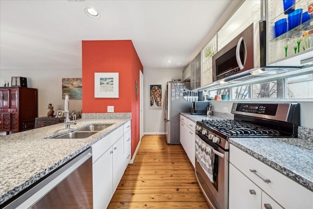 kitchen with sink, white cabinets, light hardwood / wood-style flooring, and stainless steel appliances