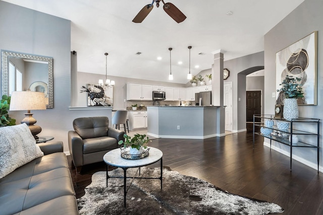 living room with ceiling fan with notable chandelier, dark hardwood / wood-style floors, and lofted ceiling