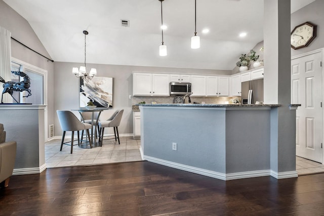 kitchen with pendant lighting, white cabinets, appliances with stainless steel finishes, wood-type flooring, and kitchen peninsula