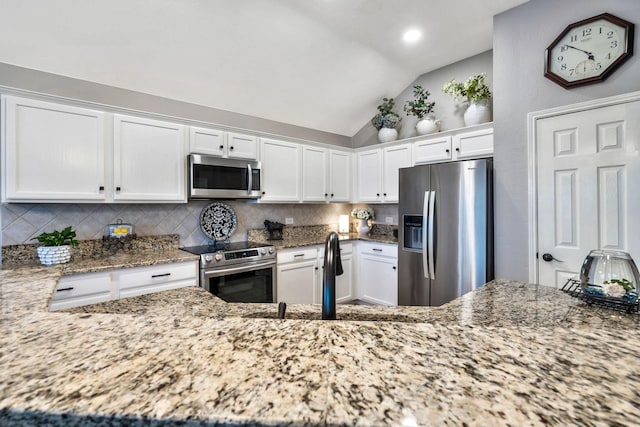 kitchen with white cabinets, stainless steel appliances, decorative backsplash, and lofted ceiling