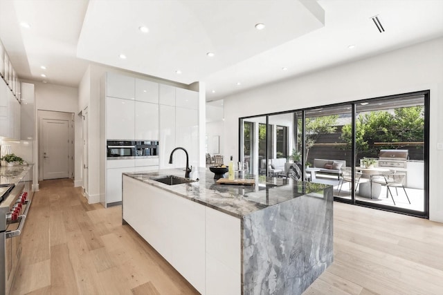 kitchen featuring sink, dark stone countertops, white cabinets, stainless steel appliances, and a spacious island