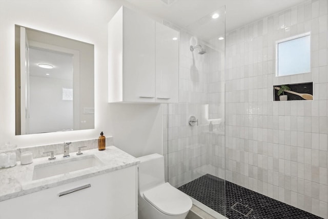 bathroom featuring tiled shower, vanity, and toilet