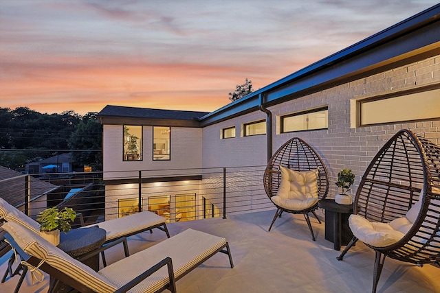 patio terrace at dusk featuring a balcony