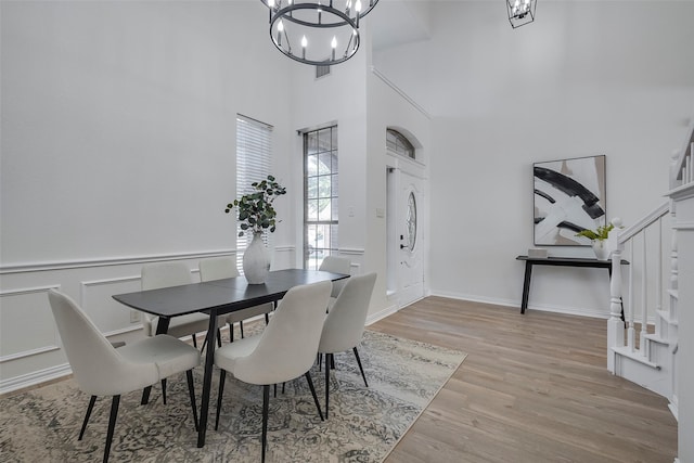 dining room featuring a high ceiling, light hardwood / wood-style flooring, and an inviting chandelier