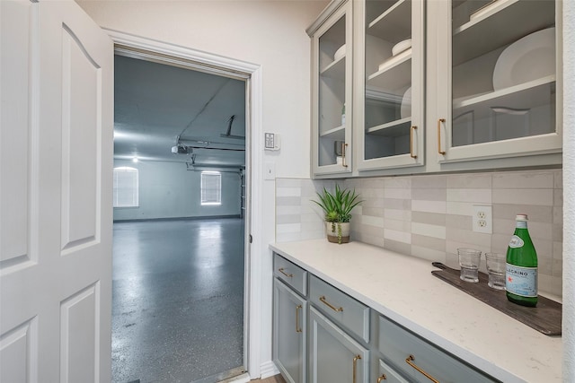 kitchen featuring gray cabinets, tasteful backsplash, and light stone counters