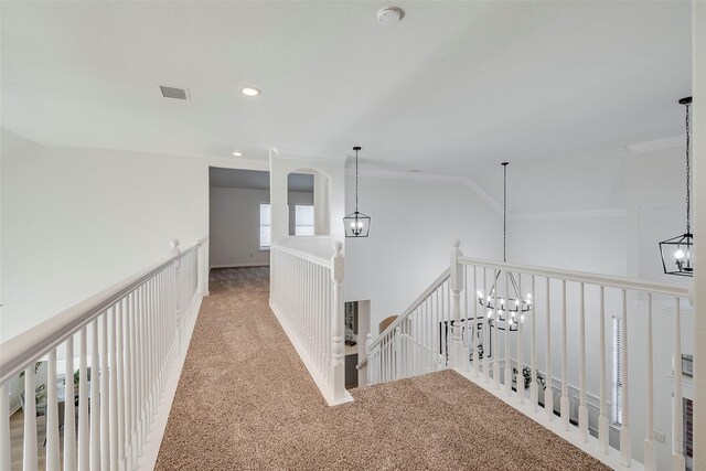 hall with crown molding, carpet, and a notable chandelier