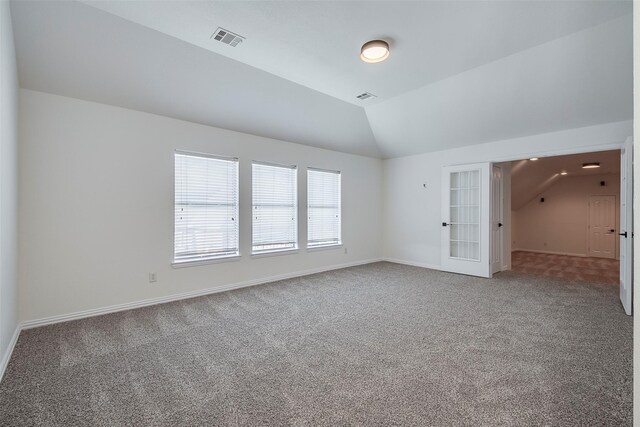 carpeted spare room featuring lofted ceiling