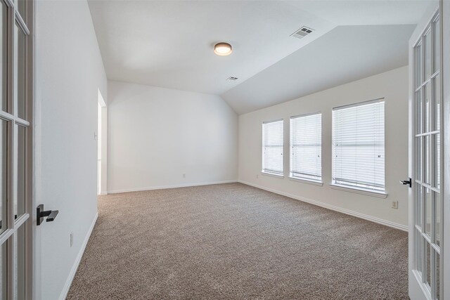 empty room featuring carpet floors, lofted ceiling, and french doors