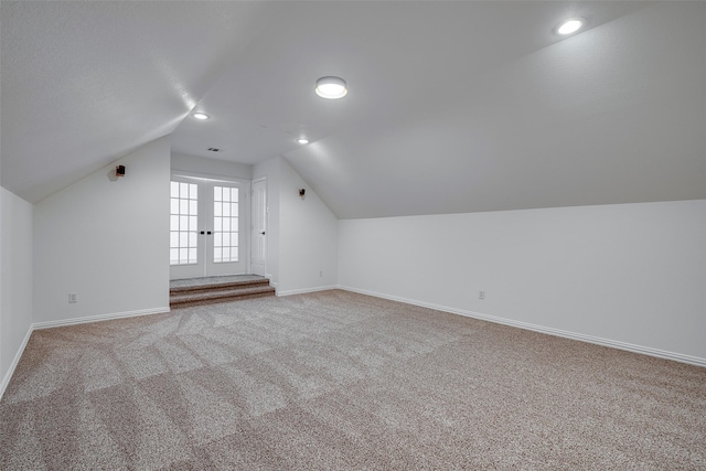 bonus room with light colored carpet and vaulted ceiling