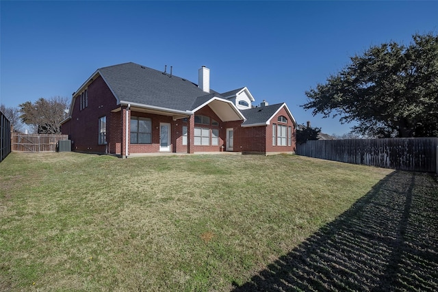 rear view of house with a lawn and central AC