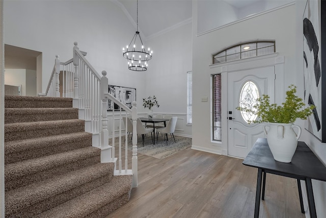 foyer with a notable chandelier, a high ceiling, crown molding, and light hardwood / wood-style floors