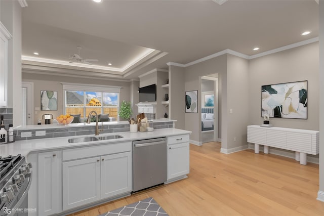 kitchen with appliances with stainless steel finishes, sink, white cabinets, and light hardwood / wood-style flooring